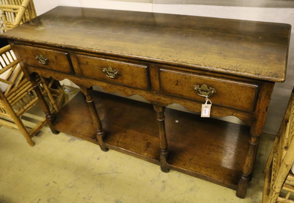 A George III style oak dresser base, fitted three drawers and undertier, width 138cm, depth 46cm, height 76cm